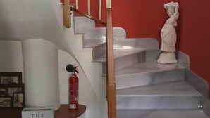 A staircase with a wooden handrail and a white statue at the top. - Palace Bed & Breakfast (Salaparuta)