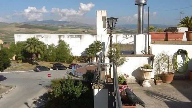 A rooftop terrace with a view of the countryside, a stop sign, and various potted plants. - Palace Bed & Breakfast (Salaparuta)