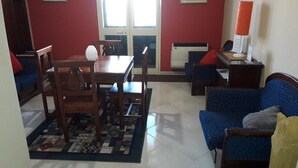 A dining area with a wooden table and chairs, a blue sofa, and a patterned rug. - Palace Bed & Breakfast (Salaparuta)