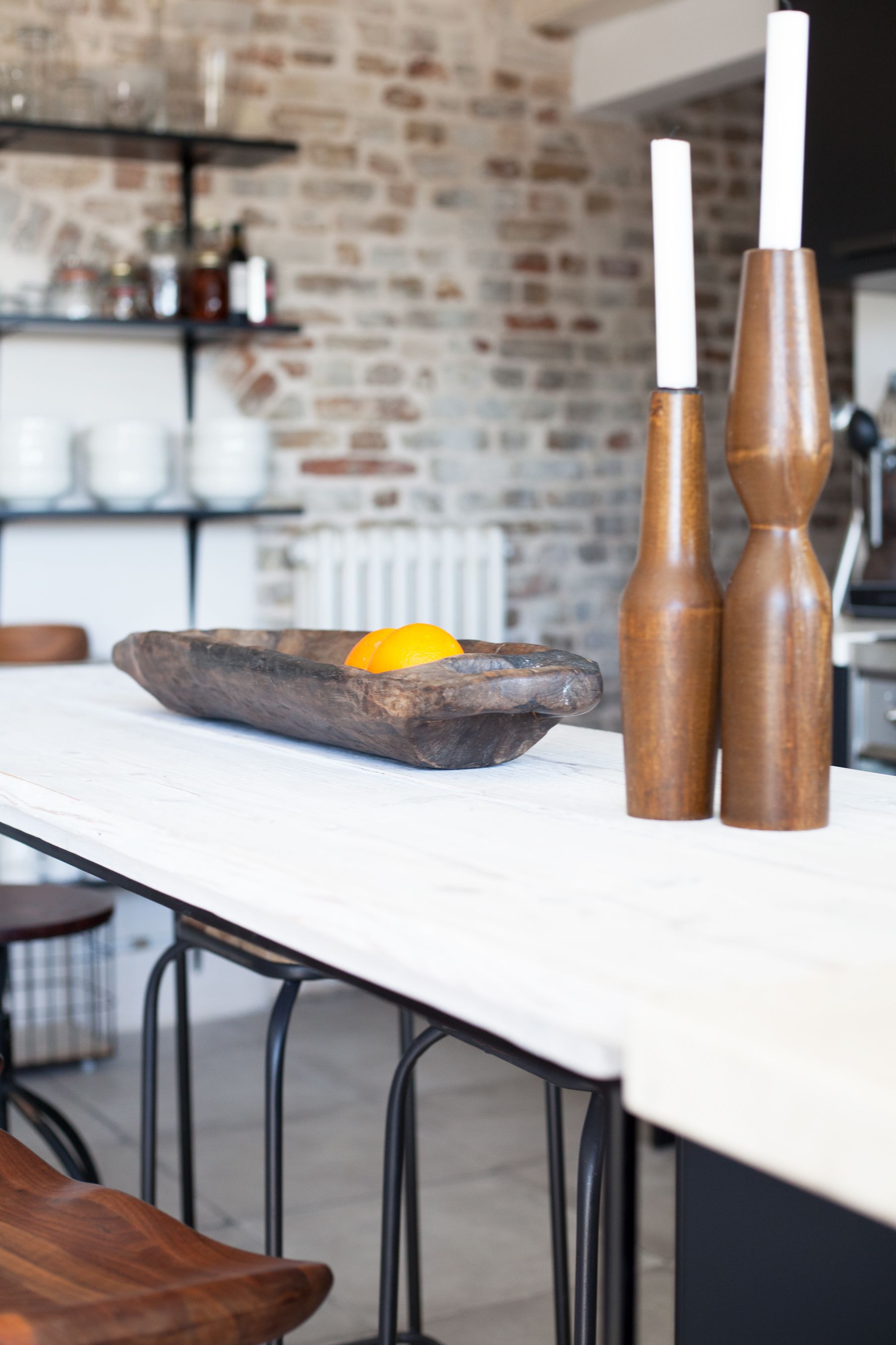 Una cocina con una encimera blanca, un cuenco de madera con una naranja y dos saleros y pimenteros de madera.