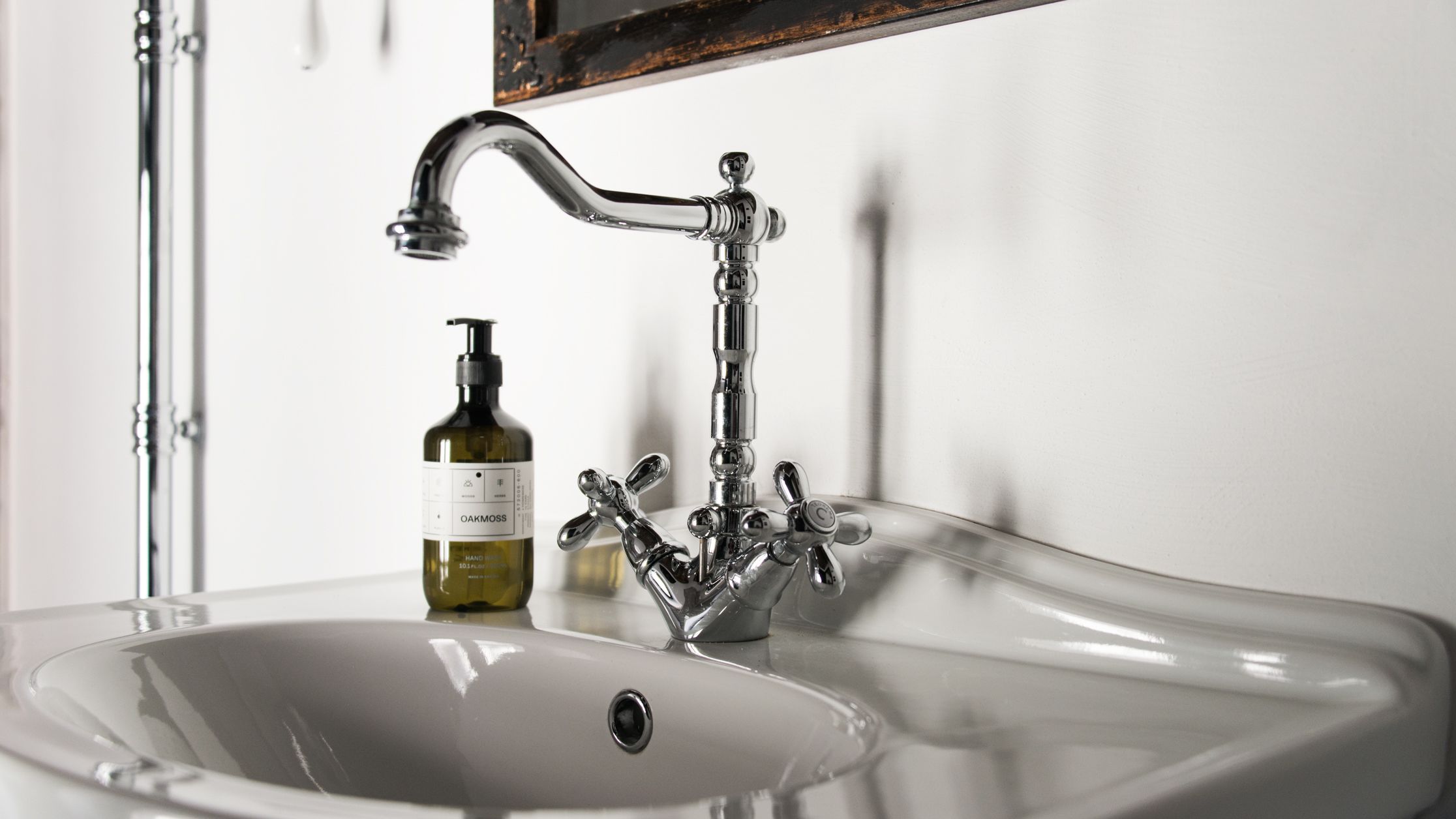 A bathroom sink with a modern faucet and a bottle of hand soap.