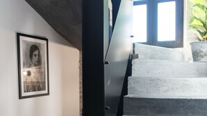 A staircase with a black handrail and a concrete finish, leading to a landing with a framed photograph on the wall. - La Pietra B&B (Grottazzolina)