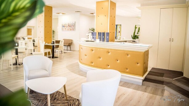 Eine moderne Hotelhalle mit Bar im Zentrum, Sitzgelegenheiten und einer Rezeption.