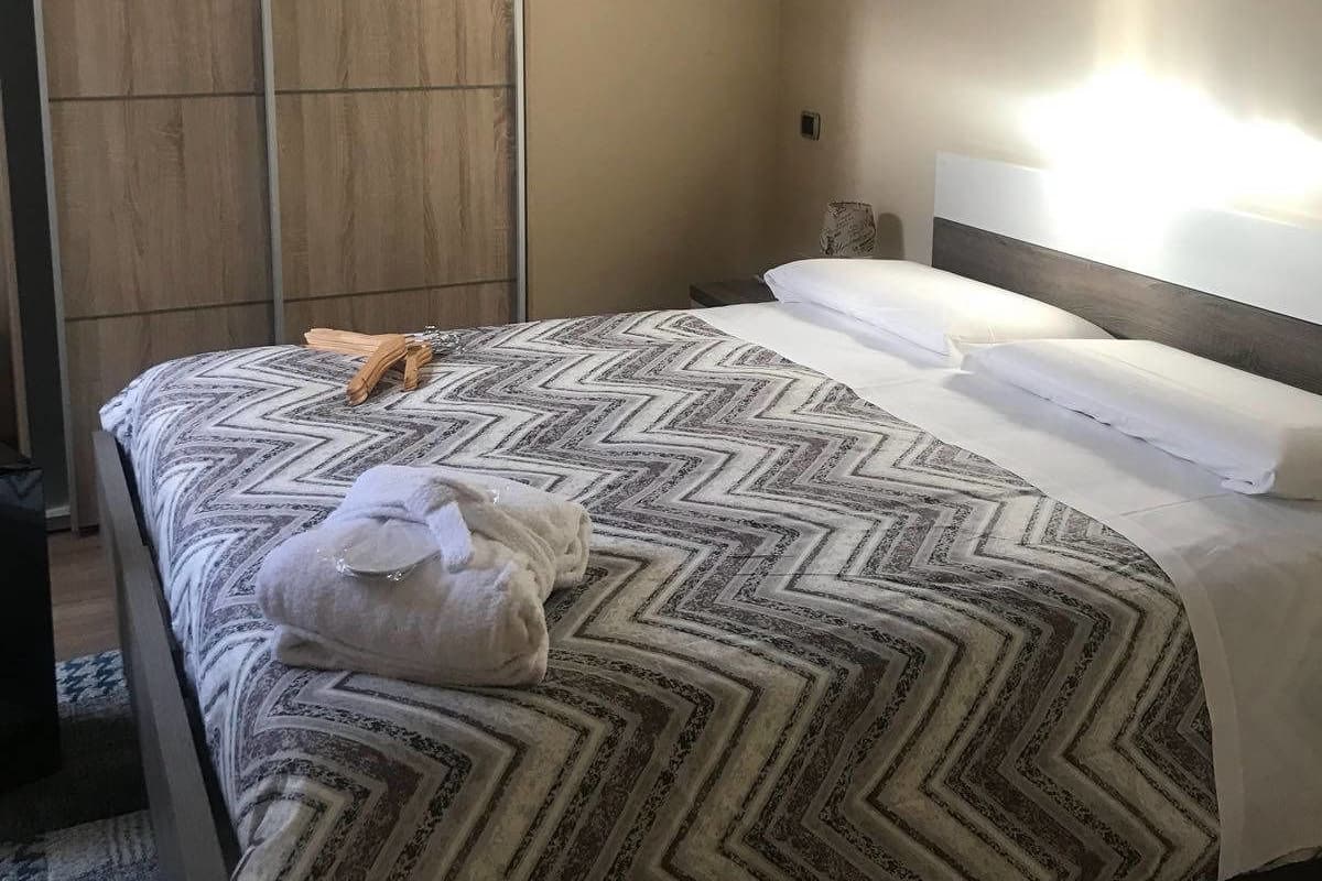 Een hotelkamer met een bed, nachtkastje en een houten garderobe.