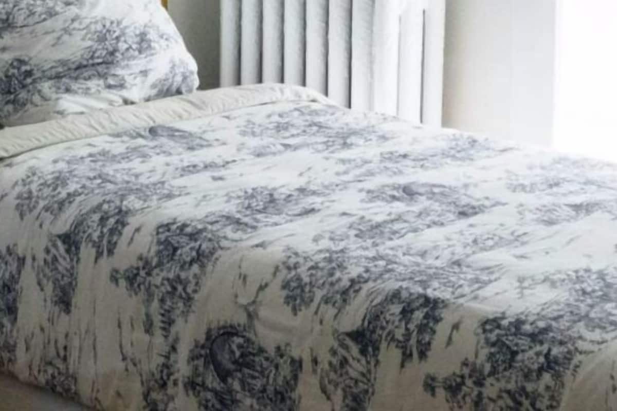 Een bed met een bloemenprintdeken en een passend kussen.