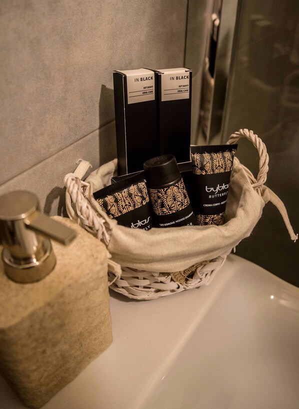 A bathroom with a white bathtub, a metal faucet, and a woven basket containing toiletries. - Hotel Lonatino (Lonato del Garda)
