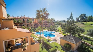 A resort with a pool area, palm trees, and a view of other buildings.