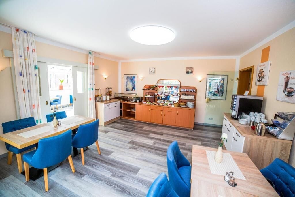 A hotel room with a dining area, kitchenette, and a bathroom.