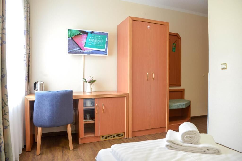 Une chambre d’hôtel équipée d’un lit, d’un bureau avec une chaise, d’une armoire et d’un téléviseur fixé au mur.