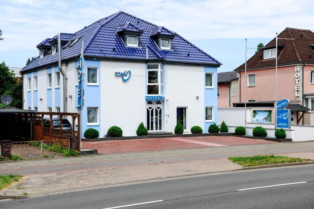 A two-story hotel with a blue roof and a sign indicating it is a hotel.