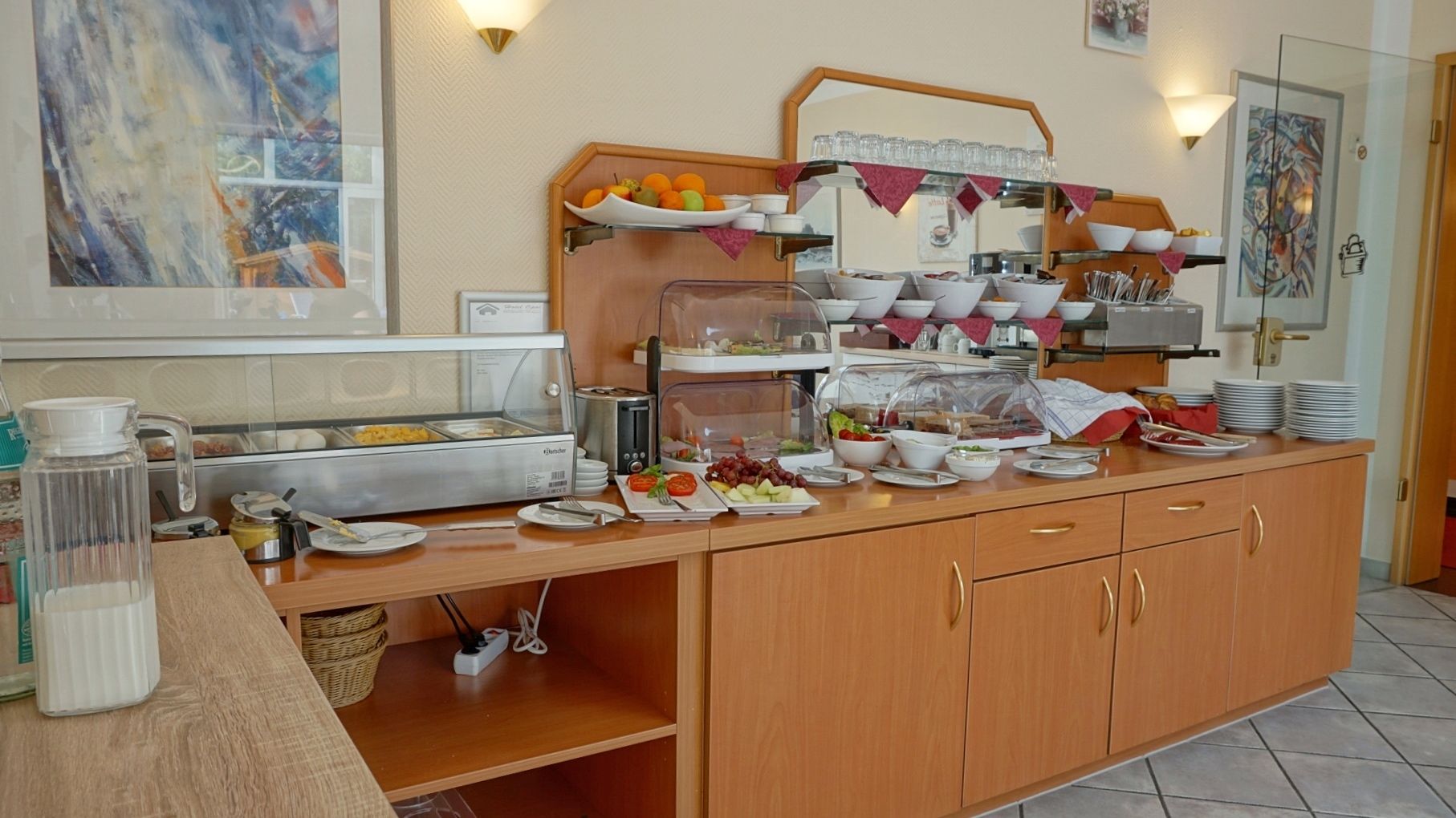 Una mesa de buffet con diversos alimentos, una estación de café y una vitrina de vidrio.
