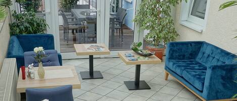 A spacious outdoor seating area with blue upholstered chairs, a wooden table, and a blue sofa.