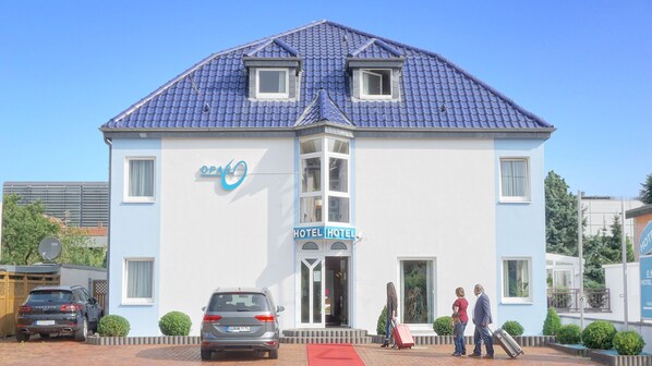 A hotel with a blue tiled roof, a central entrance, and a sign reading "OPAL HOTEL". - Hotel Opal (Laatzen)