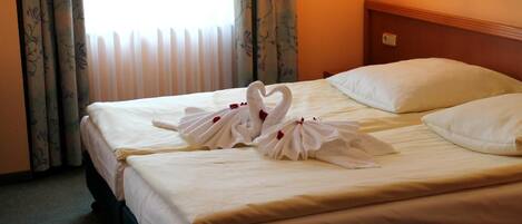 Una habitación de hotel con cama, cortinas estampadas y cabecero.