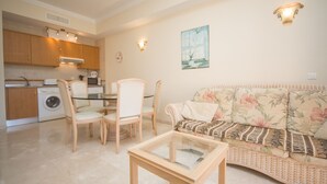 A compact living space with a kitchenette, a dining area, and a sofa with floral upholstery.