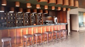 Eine Bar mit einer Holztheke, mehreren Hockstühlen und einer Auswahl an Flaschenregalen.