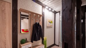 A wooden vanity with a mirror, a coat rack, and a small plant.