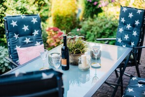 A table set outdoors with chairs, a bottle, glasses, and candles.