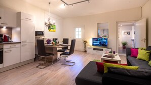 A modern living room with a sofa, TV, and dining area.