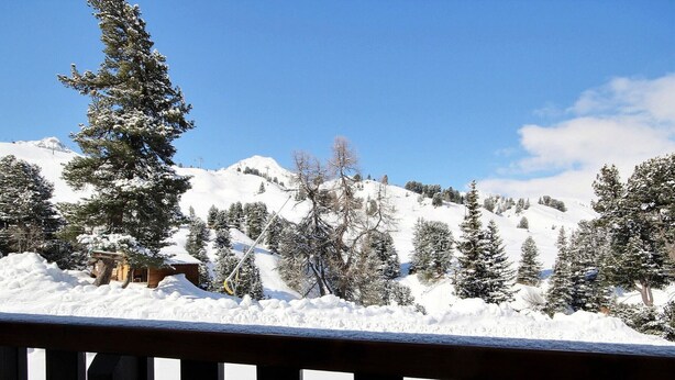 A snowy mountain landscape with a wooden cabin and snow-covered trees.