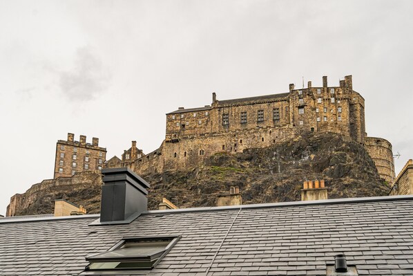 A historic stone castle on a hill with a modern building in the foreground. - 2 Bed Grassmarket Apartment (Edinburgh)