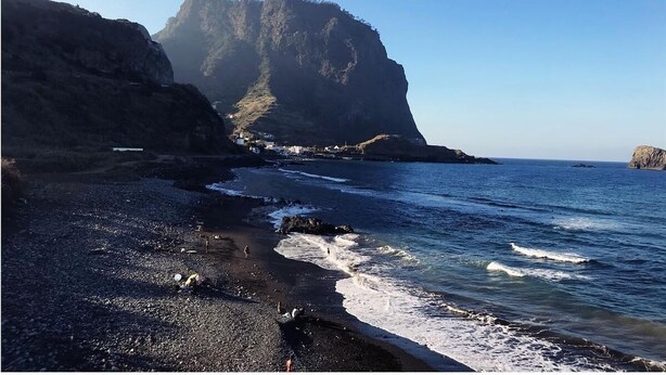 A coastal landscape with a rocky beach, a large cliff, and calm sea. - Jaca - Hostel (Machico)
