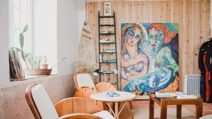 A cozy room with wooden furniture, a large painting, and a bookshelf. - Jaca - Hostel (Machico)