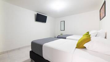 Habitación de hotel con dos camas, un televisor de pantalla plana montado en la pared y una mesita de noche.