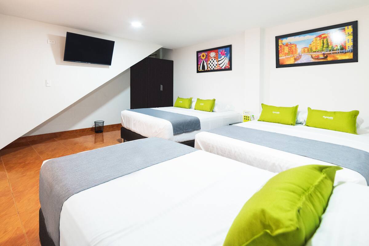 A hotel room with two beds, a TV mounted on the wall, and a painting above the beds.