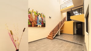 A spacious interior with a staircase, a painting on the wall, and a vase with decorative branches.