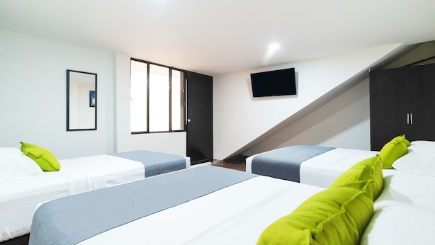 A hotel room with two beds, a flat-screen TV, a window, and a door leading to a staircase.