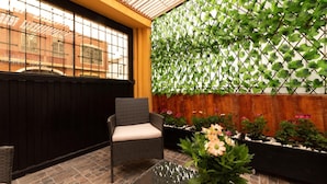 A patio area with a wicker chair, a glass table, and potted plants.