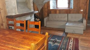 Une pièce confortable de style loft, avec une table à manger en bois, un canapé et une petite fenêtre.