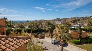 A residential area with a clear view of the sea, palm trees, and a parked delivery truck.