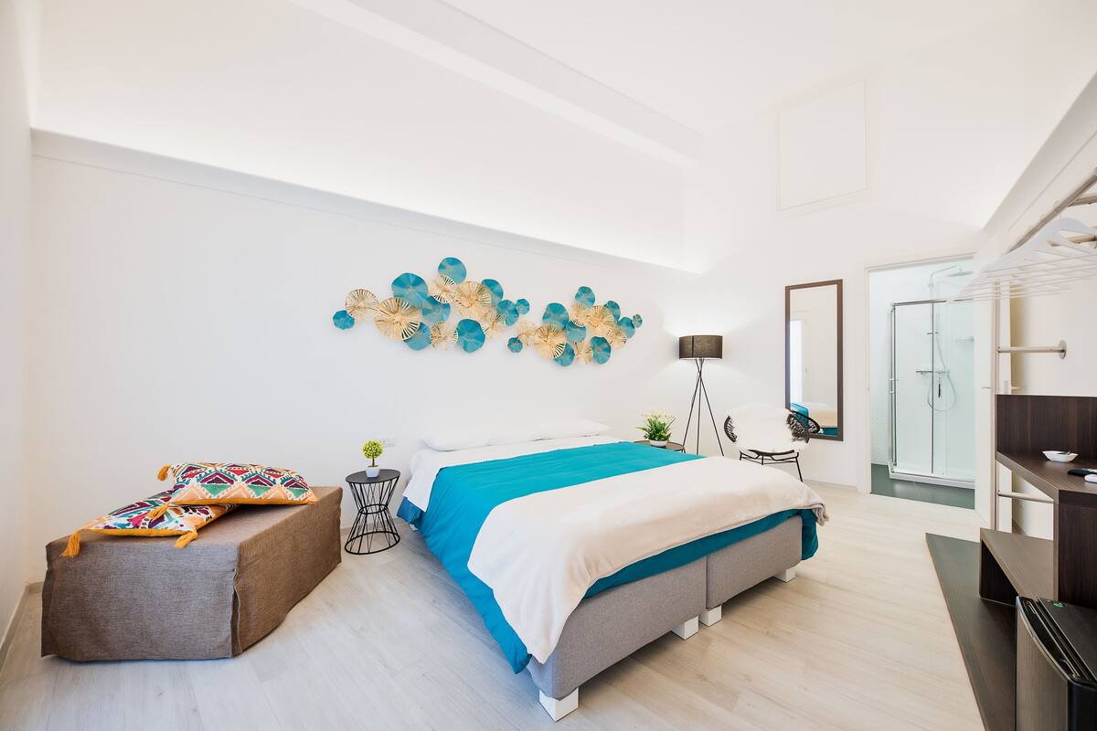 A modern bedroom with a bed, a side table, a small plant, and a wall art piece.