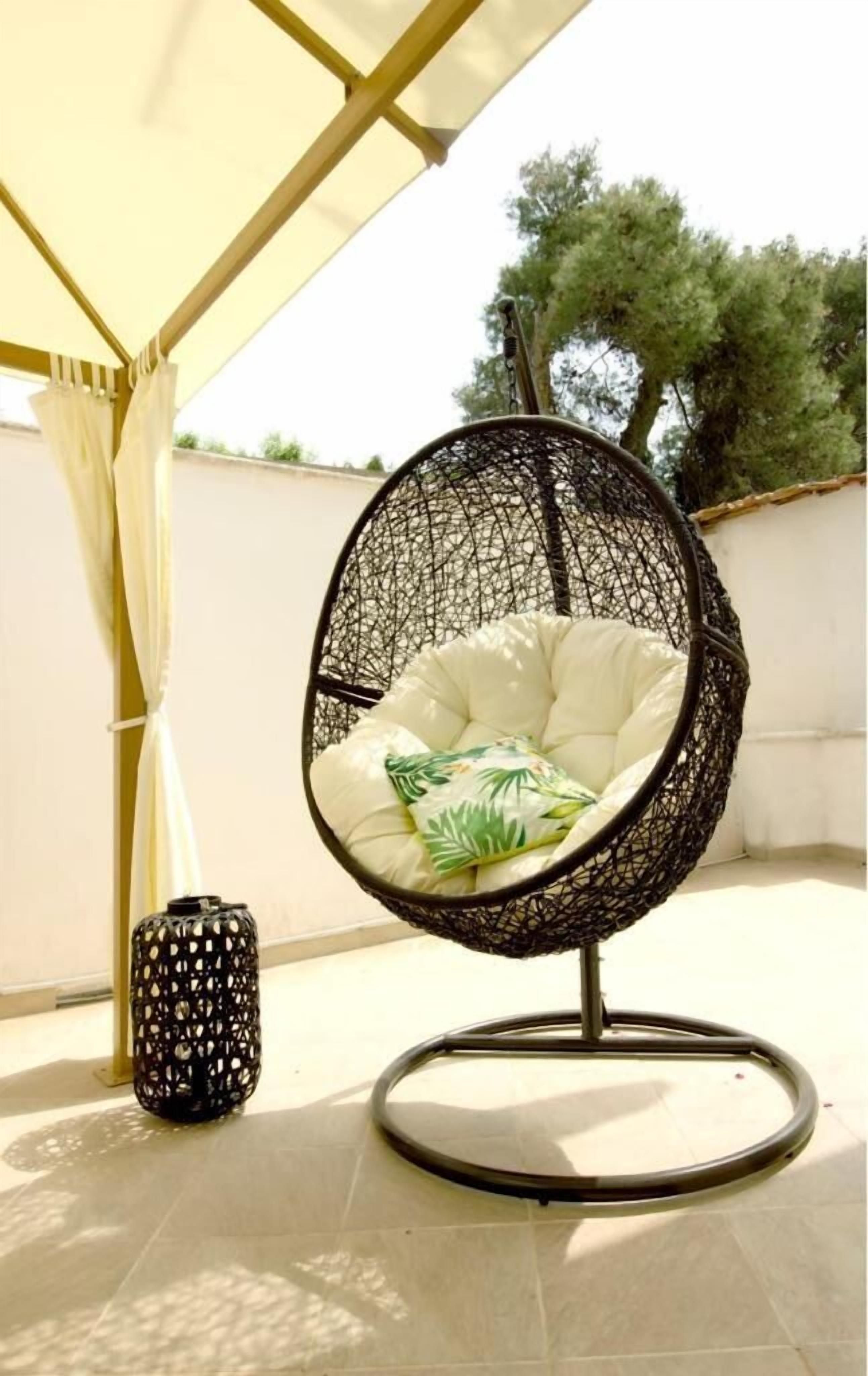 A hanging chair with a white cushion and a patterned floor lamp. - La Casa di Giovanni (Lecce)