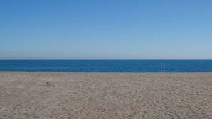 Une plage avec un ciel dégagé et une mer calme.