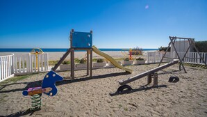 Une aire de jeux sur la plage avec un toboggan, des balançoires et une balançoire à bascule.