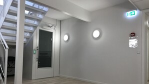 A modern interior with a staircase, a door with a handle, and a wall-mounted light fixture. - Hotel Nuka (Ilulissat)