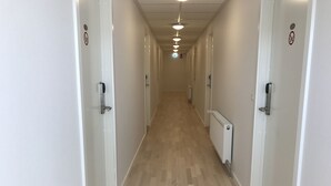 A long, narrow hallway with white walls and a wooden floor. - Hotel Nuka (Ilulissat)