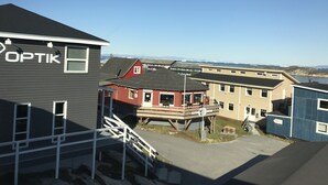 A building with a sign reading "OPTIK" and a staircase leading to a deck. - Hotel Nuka (Ilulissat)