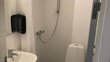 A small, compact bathroom with a white sink, toilet, and shower.