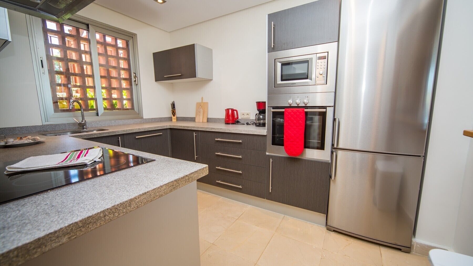 A modern kitchen with a stainless steel refrigerator, a microwave, and a built-in oven.