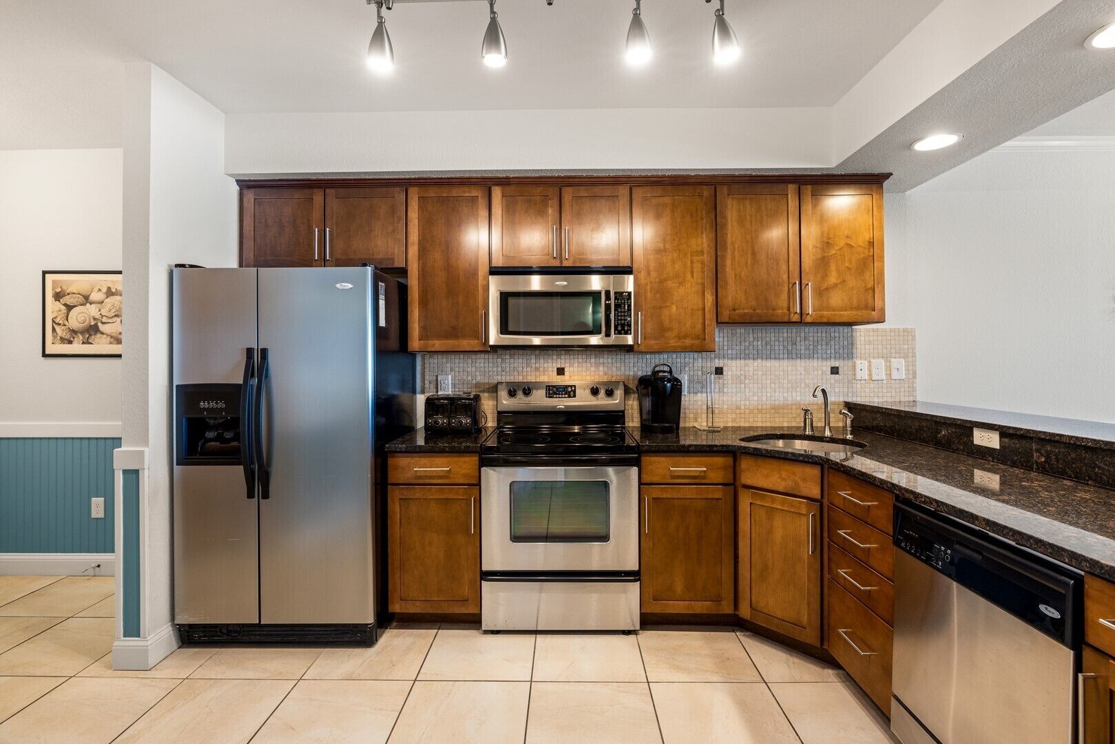 A modern kitchen with wooden cabinets, stainless steel appliances, a microwave, oven, and a dishwasher.