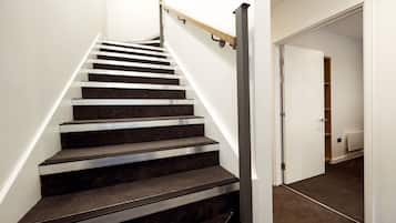 A staircase with a handrail, carpeted steps, and a white wall.