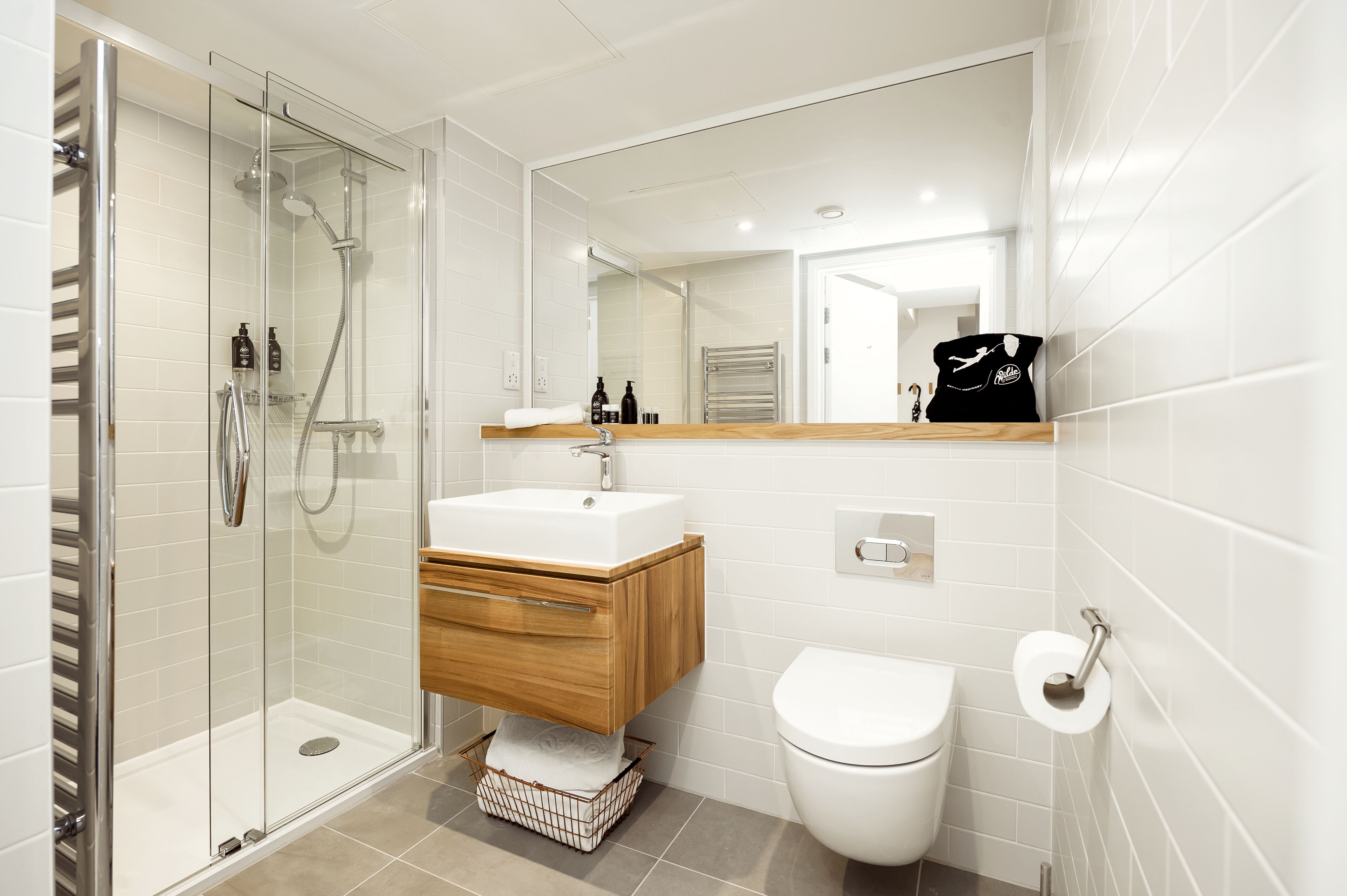 A modern bathroom with a glass-enclosed shower, a white sink with a wooden cabinet, and a toilet.