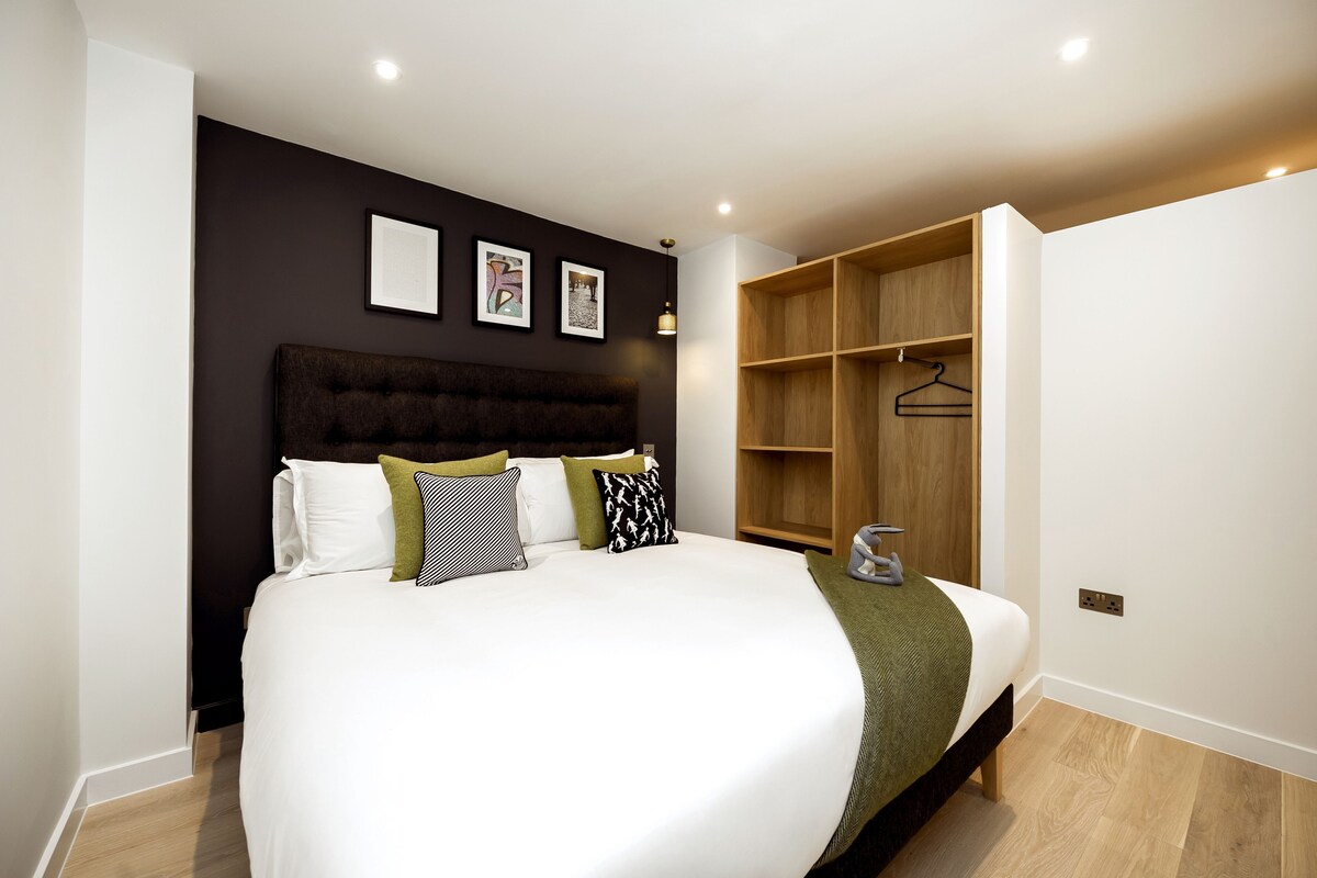 A modern bedroom with a large bed, a wooden wardrobe, and a wall-mounted shelf.