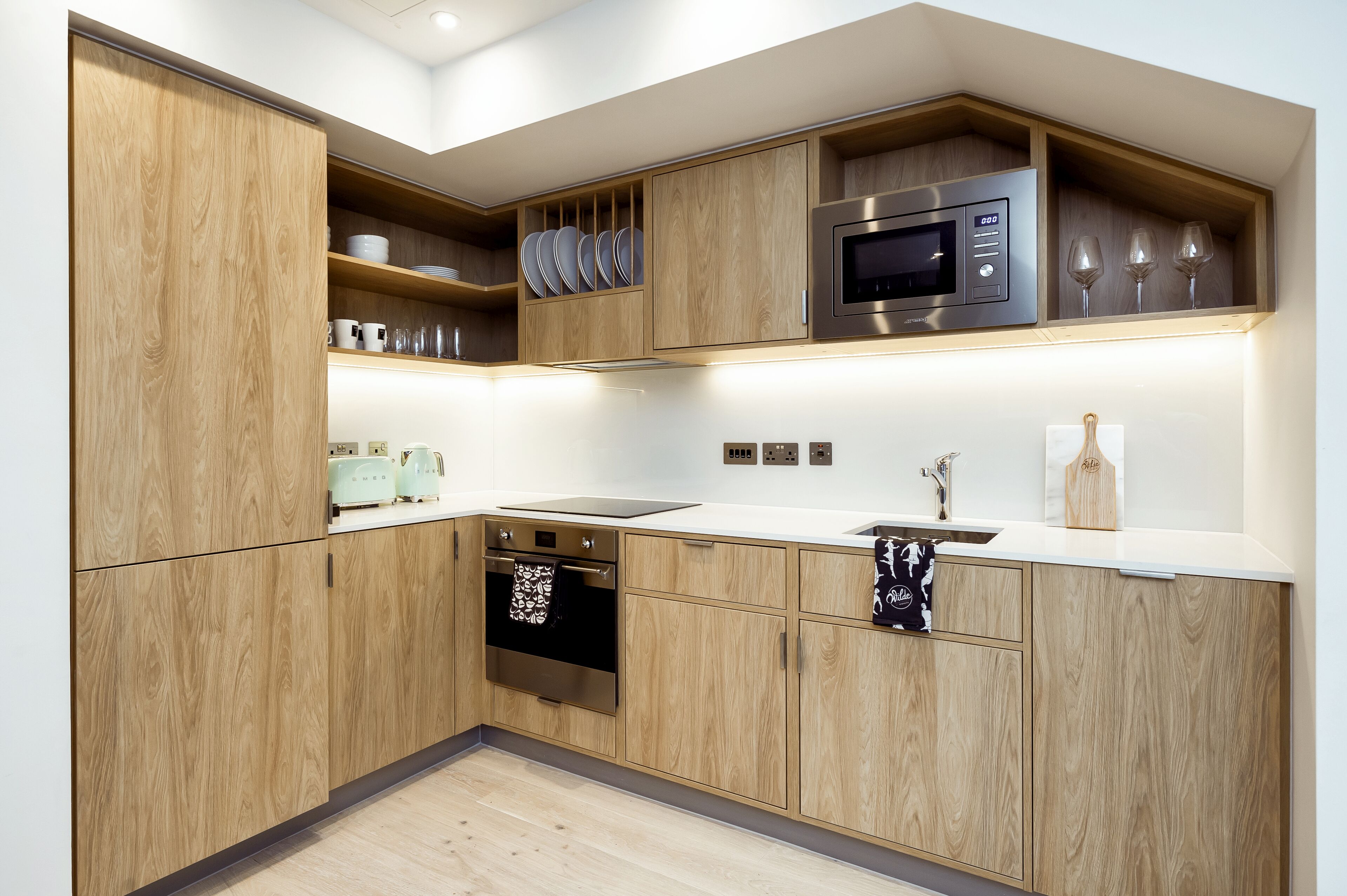 Une cuisine moderne avec des meubles en bois, un four à micro-ondes en acier inoxydable et un four encastré.