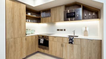Eine moderne Küche mit Holzausstattung, einer Edelstahl-Mikrowelle und einem eingebauten Backofen.