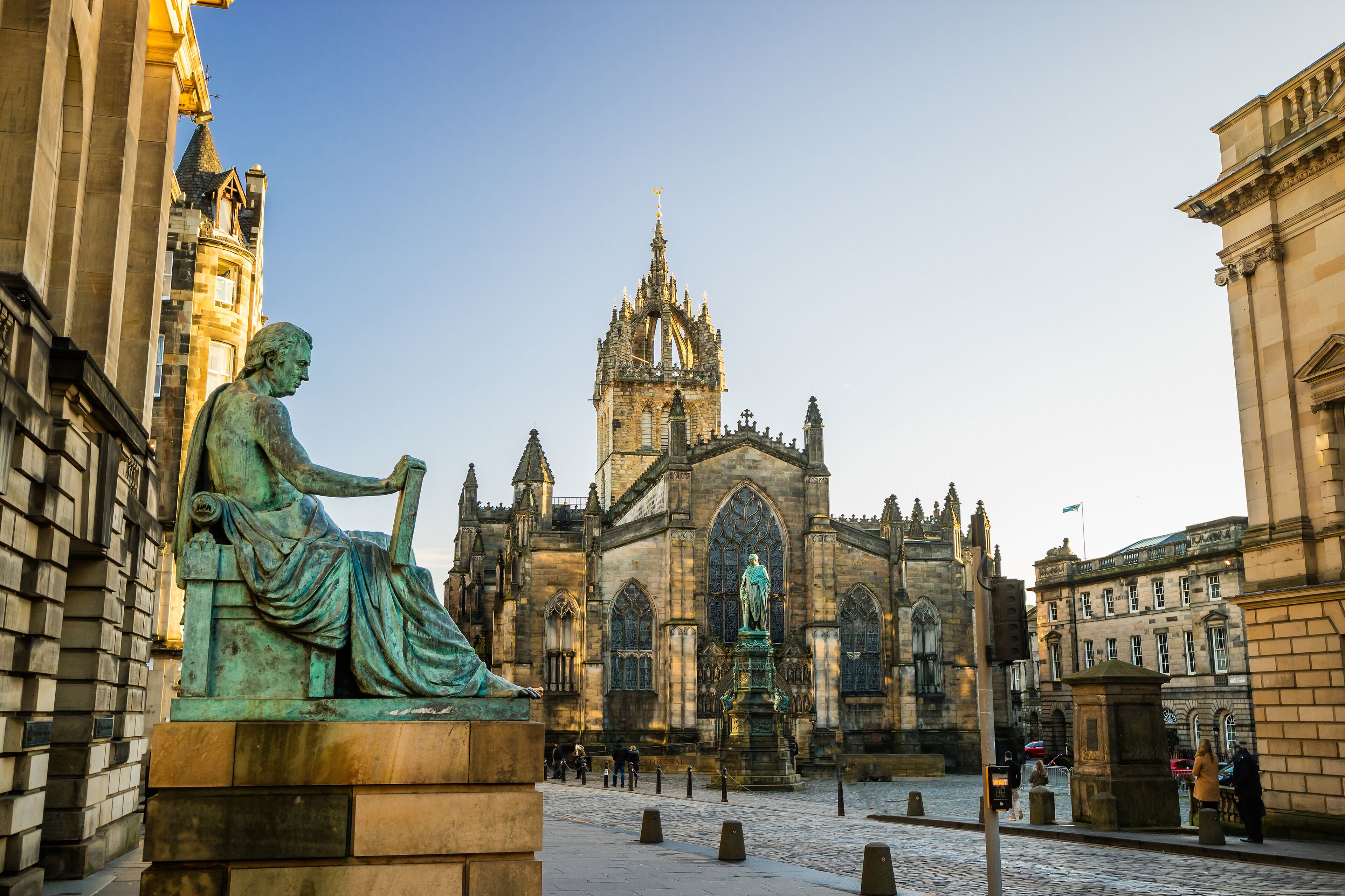 A historic building with a prominent tower and a statue in the foreground.